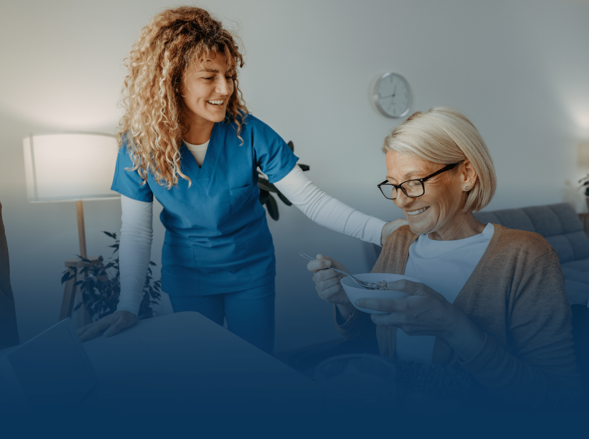 Woman helping older female eat breakfast