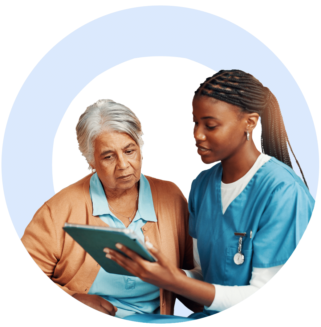 Woman in scrubs helping older woman on tablet